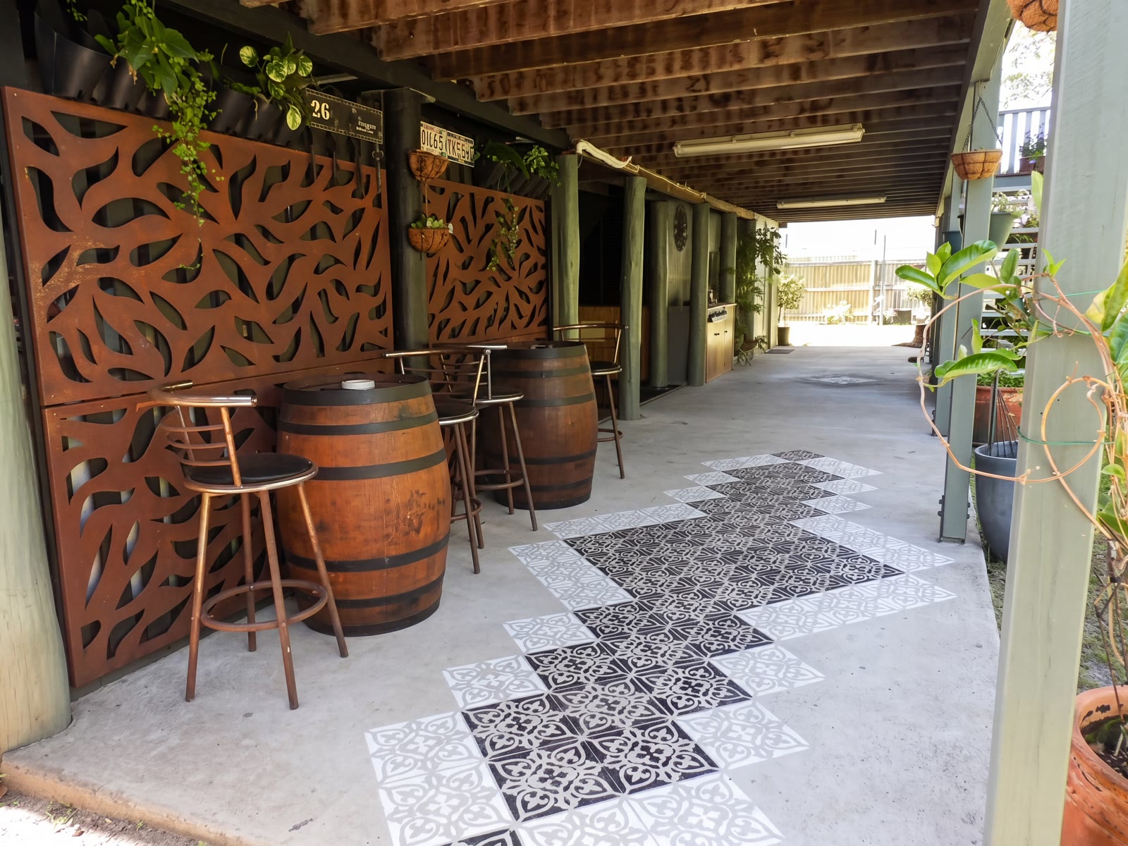 Barrel-table seating and a decorative tiled path under the house